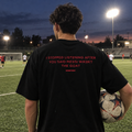 I Stopped Listening After You Said Messi Wasn't The GOAT black tee, worn on a football pitch